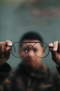 Man holding glasses to see more clearly, representing clarity