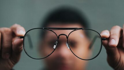 Man holding glasses to see more clearly, representing clarity