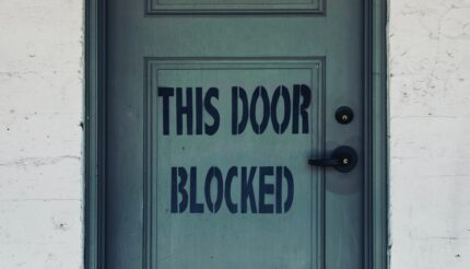 A picture of a door that says, 'this door blocked' which resembles being stuck in business