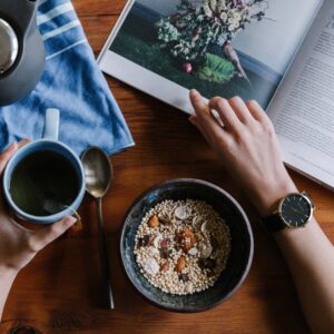 The picture is of someone drinking tea, eating breakfast and reasding in the morning