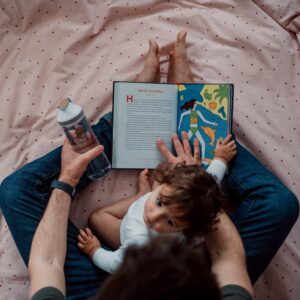 This is a picture a of business owner reading his baby a bedtime story, drinking some water to represent an evening routine