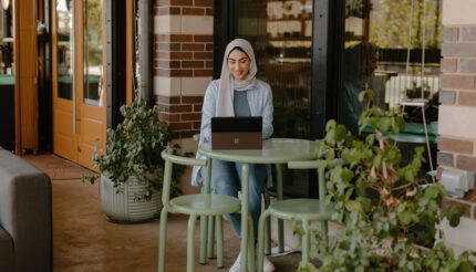 The picture is of a person looking happy on their laptop to show how knowing about your finances as a business owner makes you happier, more relaxed and in control of your business